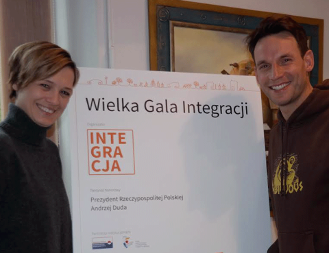 Paulina Chylewska i Tomasz Wolny stoją przy tablicy z napisem Wielka Gala Integracji 2016