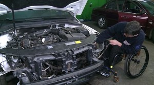 Mechanik na wózku grzebie w samochodzie, który ma otwartą maskę