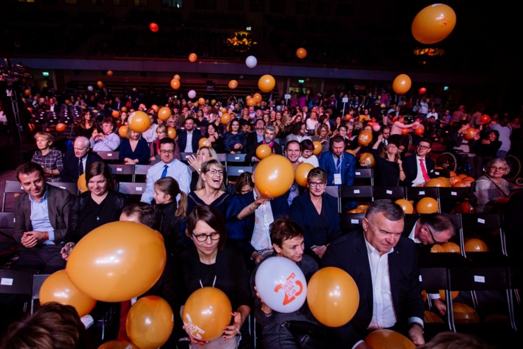 tłum publiczności na wielkiej gali bawi się spadającymi z sufitu balonikami