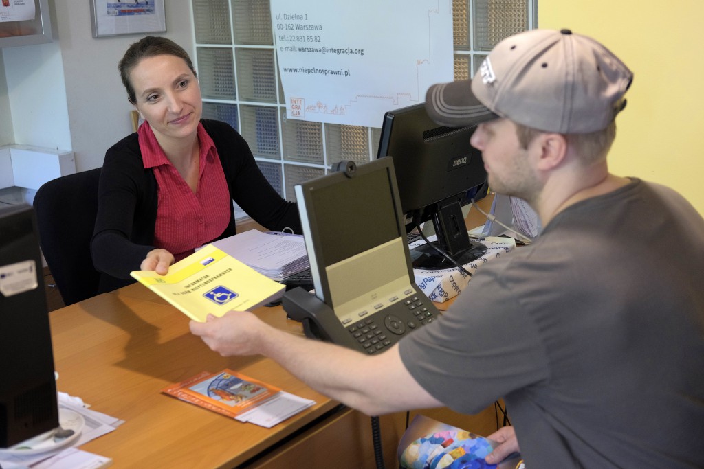 Magdalena Sarnecka przy biurku podaje broszurę informacyjną klientowi